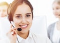 Call center in sunny office. Group of diverse operators at work. Beautiful woman in headset communicating with customers