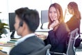 Call center worker accompanied by her team. Smiling customer support operator at work. Professional operator concept Royalty Free Stock Photo