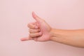 Call me hand sign or gesture  on pink background Royalty Free Stock Photo