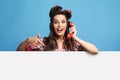 Call me. Happy young pinup woman in retro wear pointing at blank advertisement board, speaking on landline phone, mockup