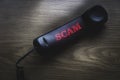 Call scam concept. A black phone with a blurry and glow text of Scam on wooden background Royalty Free Stock Photo