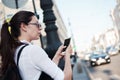 Call a taxi using the mobile application. A young woman in the city is standing near the road with a smartphone Royalty Free Stock Photo