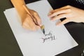 Calligrapher hands writes phrase on white paper. Phrase - Thank you. Inscribing ornamental decorated letters Royalty Free Stock Photo