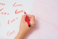 Calligrapher student practices in writing word LOVE with red marker on canvas. Creative artist freelancer working on