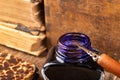 Calligraphy nib and ink in inkwell on a wooden table. Writing accessories in the old workshop