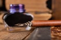 Calligraphy nib and ink in inkwell on a wooden table. Writing accessories in the old workshop Royalty Free Stock Photo