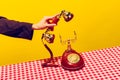 Retro objects, pop art photography. Female hand holding handset of vintage phone isolated on bright yellow background Royalty Free Stock Photo