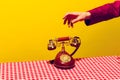 Retro objects, pop art photography. Female hand holding handset of vintage phone isolated on bright yellow background Royalty Free Stock Photo