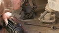 The calloused hands of a mechanic twist the coil spring ties with a wrench during DIY car repairs.