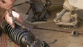 The calloused hands of a mechanic twist the coil spring ties with a wrench during DIY car repairs.