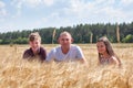 Calm adult single father with his smiling preteen children sitting in wheat stems