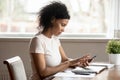 Calm african ethnic millennial woman using mobile apps on cellphone.