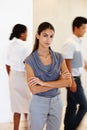 Calm amongst the storm. a confident young woman standing in a busy office.