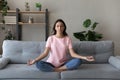 Calm Arabian woman meditating, sitting in lotus pose on couch Royalty Free Stock Photo