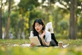 Calm Asian girl in casual clothes lying on picnic blanket and reading notes in notebook Royalty Free Stock Photo