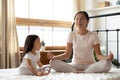 Calm Asian mother and little daughter doing yoga exercise together