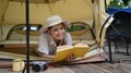 Calm asian woman reading a book, resting in her camping tent. Travel, camping and vacation concept Royalty Free Stock Photo