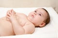 Calm baby boy lying on his back with crossed fingers on table for nappy changing, enjoying time Royalty Free Stock Photo