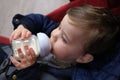 calm baby drinking milk out of a baby bottle in his stroller Royalty Free Stock Photo