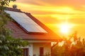 The calm background of the sunset illuminates the solar panels installed on the red-tiled roof of a modern house. Royalty Free Stock Photo