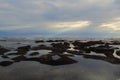 Calm beach with sunset light on blue sky clouds over horizon on the rocky beach with calm wave water. Inspirational background.