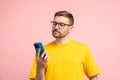 Calm bearded man in glasses looking at mobile phone screen with composed settled satisfied face Royalty Free Stock Photo