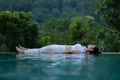 Calm of Beautiful Attractive ..Asian woman practice yoga Dead Body or Savasana pose on the pool above the Mountain peak Royalty Free Stock Photo