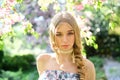 Calm blond girl enjoying spring day in floral garden filled with fresh aroma of flower blossom. Pretty young lady with