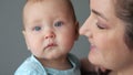 Calm blue-eyed baby girl enjoys mother careness and love