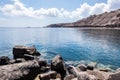 The calm blue sea of greece in santorini island seen from behind black volcanic rocks on the shore Royalty Free Stock Photo