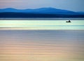 Calm blue sunset sky over the lake, silhouette of a lone boat with a fisherman, calm surface of water, lake Uvildy Royalty Free Stock Photo