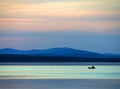 Calm blue sunset sky over the lake, silhouette of a lone boat with a fisherman, calm surface of water, lake Uvildy Royalty Free Stock Photo