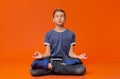 Calm boy sitting on floor and meditating in lotus position. Royalty Free Stock Photo