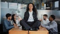 Calm businesswoman leader woman doing breathing yoga exercise taking break meditating sitting at table in office in Royalty Free Stock Photo