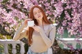 Calm caucasian lady holding cream jar in hands posing in spring garden, beauty concept Royalty Free Stock Photo