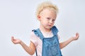 Calm confused pretty european little girl in dress spreads arms to the sides, isolated Royalty Free Stock Photo