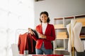 Calm curly brunette dark skinned woman on desk in office of fashion designer and holds tablet and smartphone