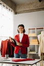 Calm curly brunette dark skinned woman on desk in office of fashion designer and holds tablet and smartphone