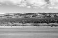 Calm desert highway empty road nowhere lonely black white mountains clouds dry adventure climate Royalty Free Stock Photo