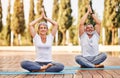 Happy senior husband and wife meditating with eyes closed in lotus position during yoga outdoors Royalty Free Stock Photo