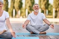 Happy senior husband and wife meditating with eyes closed in lotus position during yoga outdoors Royalty Free Stock Photo