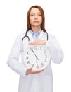 Calm female doctor with wall clock