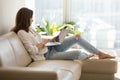 Happy female browsing internet sitting on sofa at home Royalty Free Stock Photo
