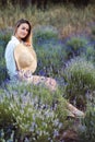 Calm Girl Sits in Lavender Meadow and enjoys Beauty and silence. Woman holds Hat in front of her