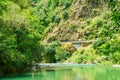 Calm green waters of mountain river flowing along a forested cliffs. Waioeka Gorge, North Island, New Zealand Royalty Free Stock Photo