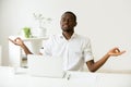 Calm happy african man meditating at office desk with laptop Royalty Free Stock Photo