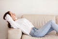 Calm happy millennial woman relaxing on comfortable couch at hom