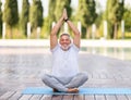 Calm happy senior man sitting in lotus pose on mat during morning meditation in park Royalty Free Stock Photo