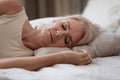 Calm serene older woman sleeping alone in bed, closeup view