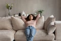 Calm Hispanic woman rest on sofa breathe fresh air